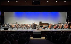 a concert with a conductor and orchestra on stage