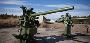 a couple of large green guns sitting on top of a cement ground