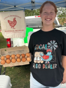 a woman holding a tray of eggs under a tent