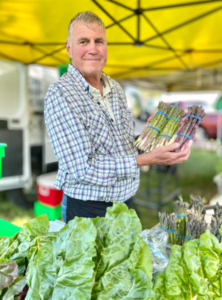 a man holding a bunch of green vegetables