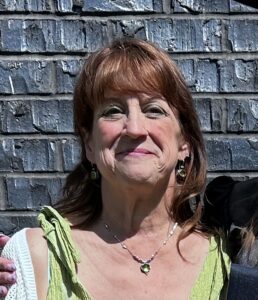a woman standing next to a dog in front of a brick wall