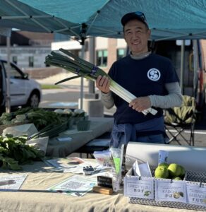 a man holding a bunch of flowers at a farmers market
