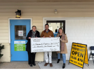a group of people standing in front of a building holding a large check