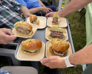a group of people sitting around a table with plates of sandwiches