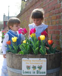 two children are looking at flowers in a barrel