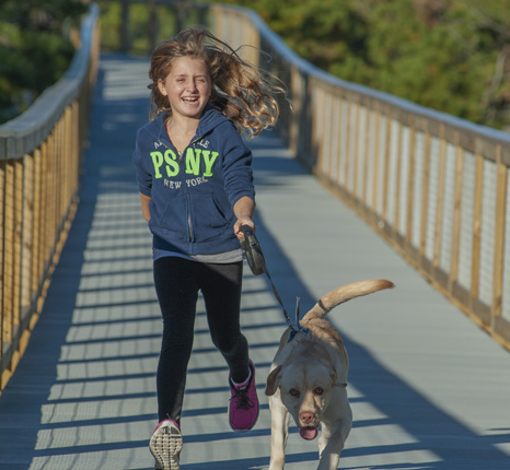 a young girl running with her dog on a bridge