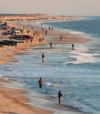 people are walking on the beach near the water