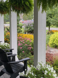 two black chairs sitting on a porch next to flowers