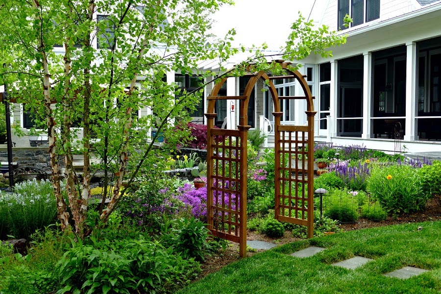 a garden with flowers and trees in front of a house